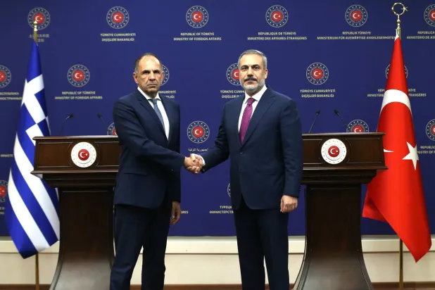 مصافحة بين وزيريْ خارجية تركيا هاكان فيدان واليونان يورغوس يرابيتريتيس في أنقرة (إ.ب.أ)
