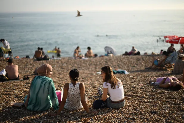 سيدات يستمتعن بالشمس على شاطئ برايتون في جنوب إنجلترا (أ.ف.ب)