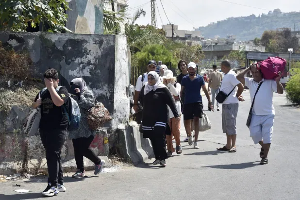 فلسطينيون ينزحون عن مخيم عين الحلوة هرباً من المعارك (إ.ب.أ)