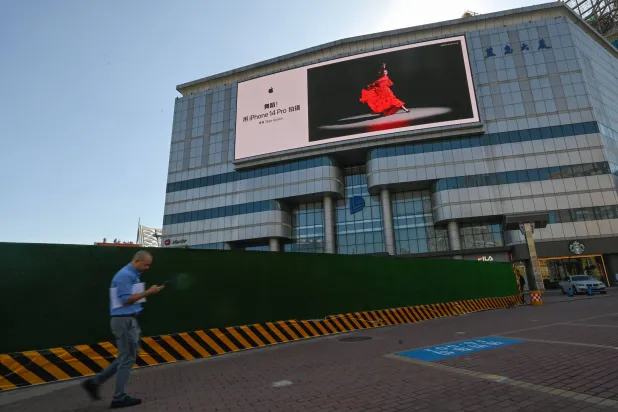 رجل يمر أمام إعلان لـ«آبل آيفون» في بكين في 12 سبتمبر 2023 (أ.ف.ب)