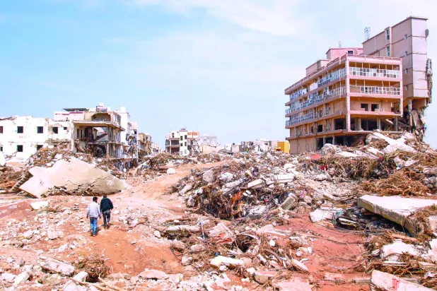 
رجلان يمران وسط الدمار الناجم عن الإعصار في مدينة درنة شرق ليبيا أمس (أ.ف.ب)