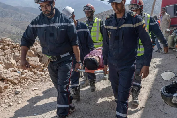عمال إنقاذ يقومون بإجلاء ناجية بعد أن أنقذوها من تحت أنقاض منزل انهار بسبب الزلزال في قرية إيمي نتالا بالقرب من أمزميز في 12 سبتمبر 2023 (أ.ف.ب)