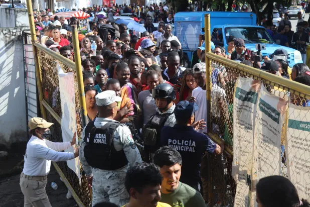 مهاجرون يصطفون لتسوية وثائقهم في بلدية تاباتشولا بولاية تشياباس المكسيكية (إ.ب.أ)