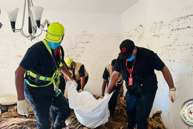 چند نفر از اعضای سازمان جستجو و شناسایی افراد مفقود الاثر در حال کشیدن جسد یک نفر از زیر آوار در درنه (سازمان جستجو وشناسایی افراد مفقود الاثر)