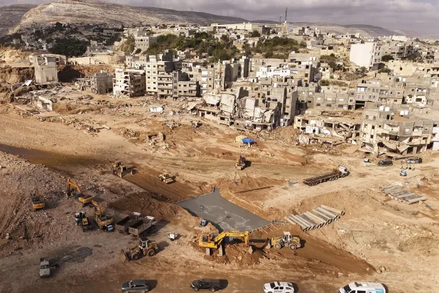 عمال البناء يقومون ببناء جسر يربط بين الأجزاء الشرقية والغربية من درنة، والتي جرى تقسيمها بسبب انهيار سد في أعقاب الفيضانات الأخيرة الناجمة عن العاصفة «دانيال» (أ.ب)