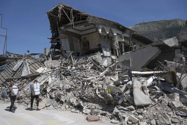 شبان يحملون إمدادات الإغاثة في 26 أبريل 2023 بالقرب من الأنقاض بمدينة أنطاكيا القديمة في جنوب تركيا الذي ضربه زلزال مدمر (د.ب.أ)