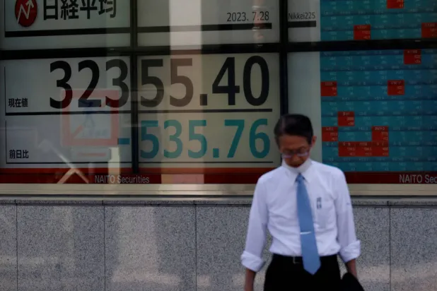 رجل يسير أمام لوحة إلكترونية تعرض حركة الأسهم على مؤشر «نيكي» الياباني وسط العاصمة طوكيو (رويترز)