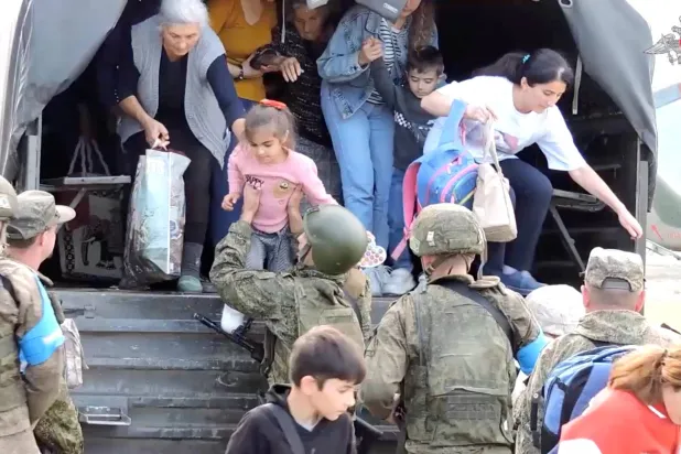 مدنيون أرمن يترجلون من شاحنة عسكرية خلال عملية إجلاء من ناغورنو كاراباخ أجرتها قوة حفظ السلام الروسية (رويترز)