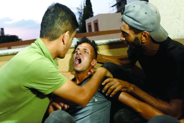 غزہ کی پٹی اور اسرائیل کو الگ کرنے والی باڑ کے قریب مارے جانے والے نوجوان یوسف رضوان کے رشتہ دار رو رہے ہیں (رائٹرز)