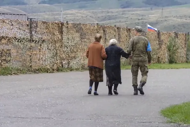 صورة مأخوذة من مقطع فيديو نشرته الخدمة الصحافية لوزارة الدفاع الروسية تُظهر جندياً من قوة حفظ السلام الروسية يُجلي مدنيين في مكان لم يُكشف عنه في ناغورنو كاراباخ (إ.ب.أ)