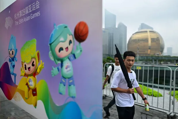 رجل يمر من أمام ملصق خاص بـ«دورة الألعاب الآسيوية» في الصين (أ.ف.ب)