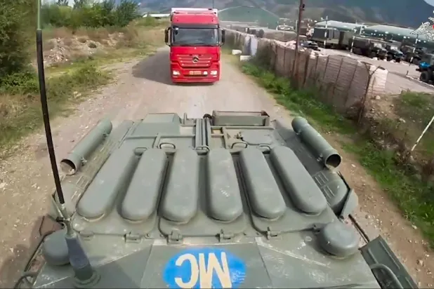 لقطة مأخوذة من شريط فيديو وزعته وزارة الدفاع الروسية لآلية عسكرية روسية من قوة حفظ السلام تواكب شاحنة تنقل مساعدات إنسانية إلى كاراباخ (أ.ب)