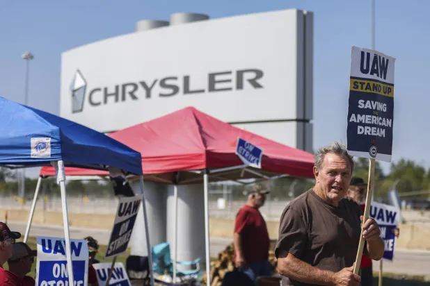مضربون عن العمل يحملون لافتات أمام مصنع «كرايسلر» لصناعة السيارات الأميركية (أ.ب)