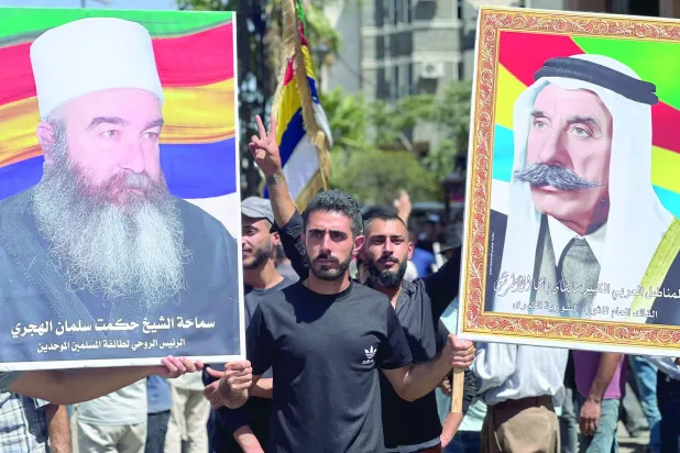 محتجون في السويداء يرفعون صورة الشيخ حكمت الهجري (يسار) وصورة الزعيم الدرزي التاريخي سلطان باشا الأطرش في 15 سبتمبر (إ.ب.أ)
