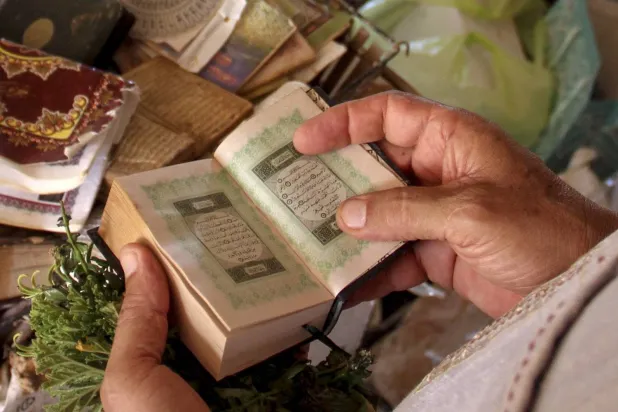 رجل يمسك بنسخة من المصحف الشريف (أرشيفية - أ.ب)