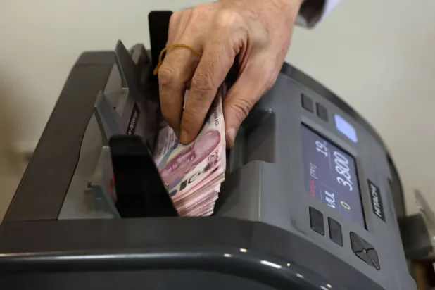 موظف بأحد البنوك في العاصمة التركية أنقرة يقوم بعدّ أوراق نقدية بينما تهاوت العملة لمستوى متدنٍّ يوم الثلاثاء (أ.ف.ب)