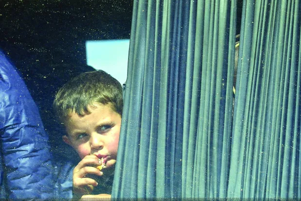 
طفل ينظر من شباك حافلة لاجئين أرمن في طريقها إلى أرمينيا الثلاثاء (رويترز)