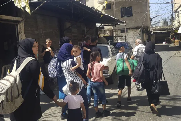 نساء وأطفال أثناء الهروب من الاشتباكات في عين الحلوة في 17 سبتمبر (أ.ب)