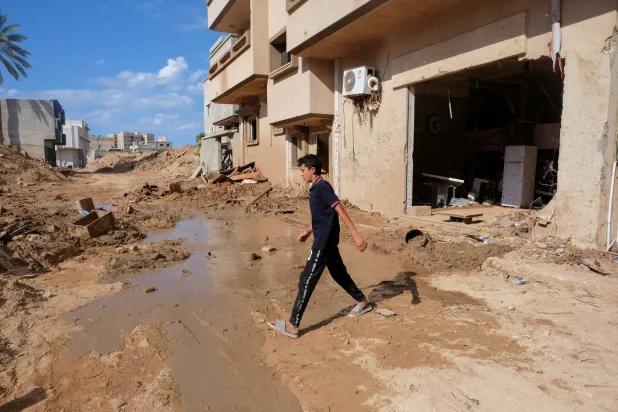 طفل ليبي يمر بالقرب من منزله المدمر في مدينة درنة (رويترز)