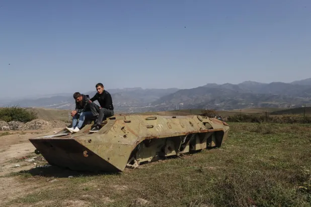 الأرمينيون من كاراباخ يستريحون على جانب الطريق بعد عبور الحدود الأذربيجانية بالقرب من قرية كورنيدزور (إ.ب.أ)