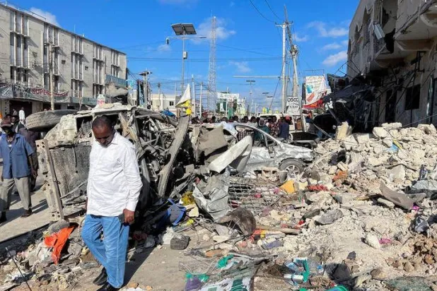 رجل يسير بجوار حطام سيارات مدمرة بالقرب من أنقاض مبنى في مكان انفجار بمقديشو الصومال في 30 أكتوبر 2022 (رويترز)