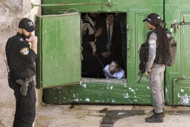 يهود أرثوذكس خلف باب المسجد الأقصى السبت بينما الشرطة الإسرائيلية تحرس خلال عطلة عيد العرش  (إ.ب)