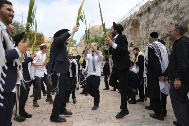 يهود أرثوذكس يمارسون طقوس صلاة بمناسبة عيد العرش خارج باب الأسباط للمسجد الأقصى (إ.ب.أ)