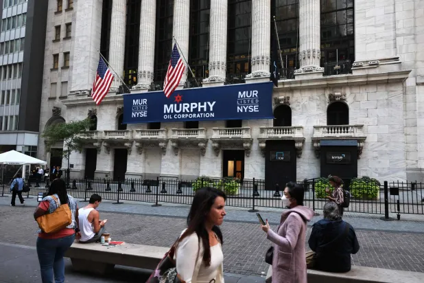 مشاة في شارع «وول ستريت» أمام مقر بورصة نيويورك الأميركية (أ.ف.ب)