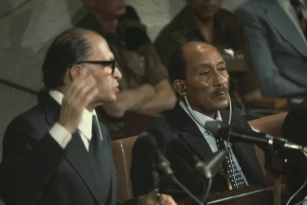 رئيس الوزراء الإسرائيلي الراحل مناحيم بيغن يخاطب الكنيست بينما يستمع الرئيس المصري الراحل أنور السادات في القدس عام 1977 (غيتي)