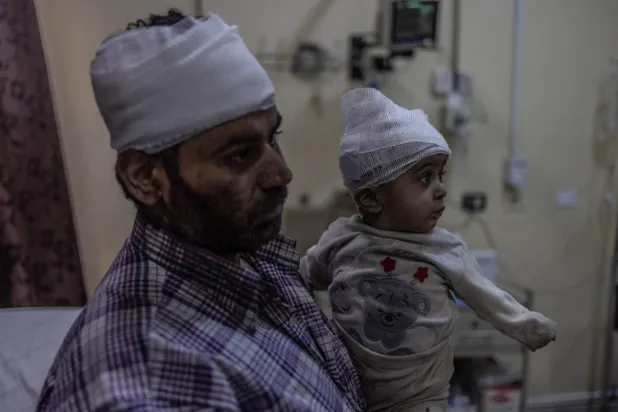 رجل وطفله بعدما أصيبا في القصف على جسر الشغور الجمعة (د.ب.أ)