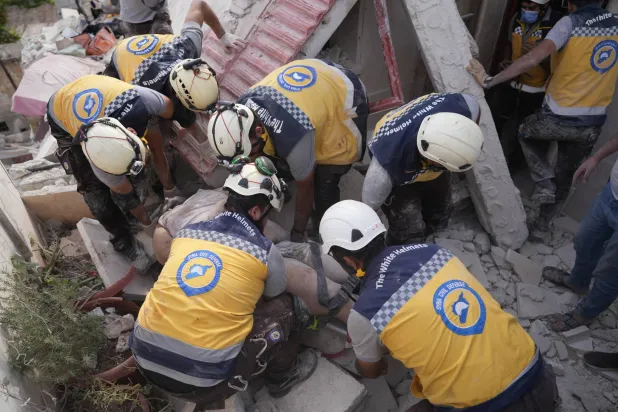 مسعفون من «الخوذ البيضاء» يحاولون إنقاذ مصابين من تحت الأنقاض في إدلب الأحد (إ.ب.أ)