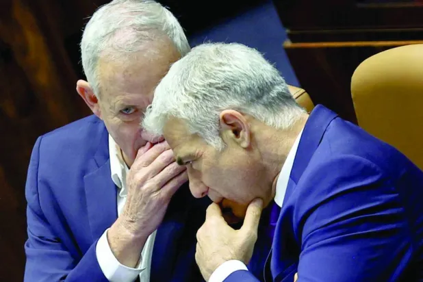 حوار هامس بين غانتس ولبيد بجلسة للكنيست الإسرائيلي في يونيو 2022 (رويترز)