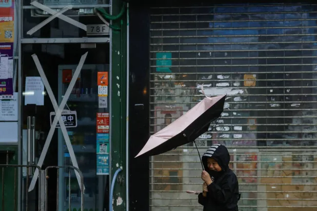 طفل يكافح رياحاً قوية ومطراً مع اقتراب إعصار «كوينو» في هونغ كونغ (رويترز)