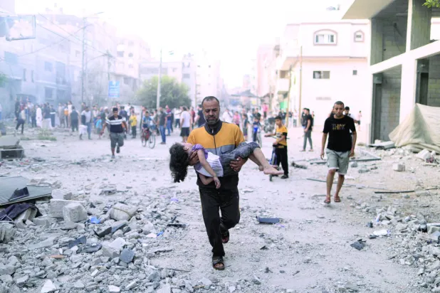 کل غزہ کی پٹی کے جنوب میں خان یونس میں اسرائیلی حملے کے بعد ایک فلسطینی شخص زخمی بچی کو اٹھائے بھاگ رہا ہے۔ (اے ایف پی)