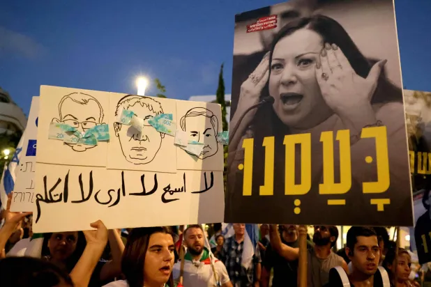 مظاهرة ضد الحكومة الإسرائيلية في تل أبيب وبينها لافتة باللغة العربية (أ.ف.ب)