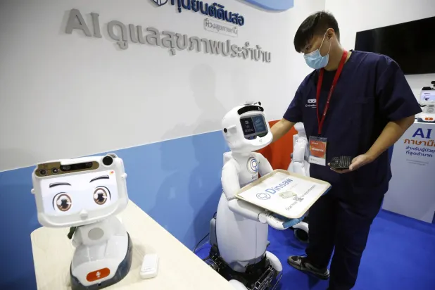 موظف يقوم بتشغيل الروبوتات الذكية المستخدمة بقطاع الرعاية الصحية في بانكوك (إ.ب.أ)