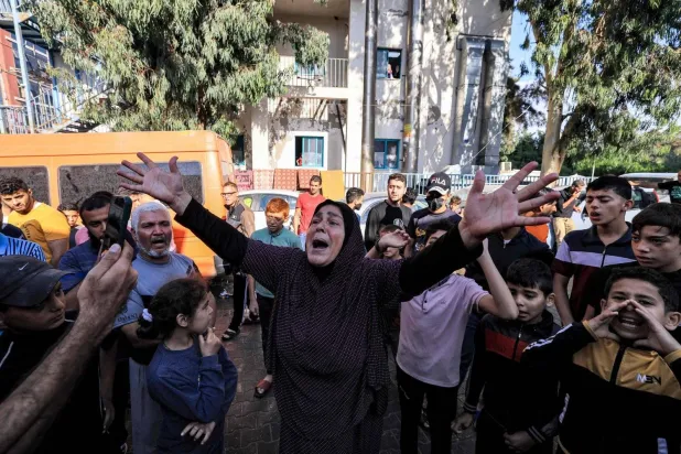 A woman reacts as people gather at the site of the Ahli Arab hospital in central Gaza on October 18, 2023 in the aftermath of an overnight blast there. (Photo by MAHMUD HAMS / AFP)
