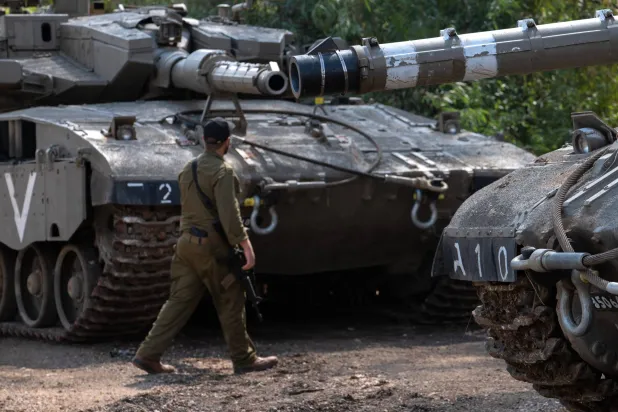 ایک اسرائیلی فوجی لبنان کی سرحد کے قریبی علاقے میں مرکاوا ٹینکوں کے درمیان سے گزر رہا ہے (ای پی اے)