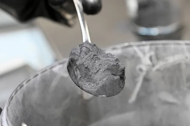 عامل يحمل ملعقة مليئة بالغرافيت في أحد مصانع إنتاج بطاريات السيارات التابعة لشركة «فولكسفاغن» الألمانية (رويترز)