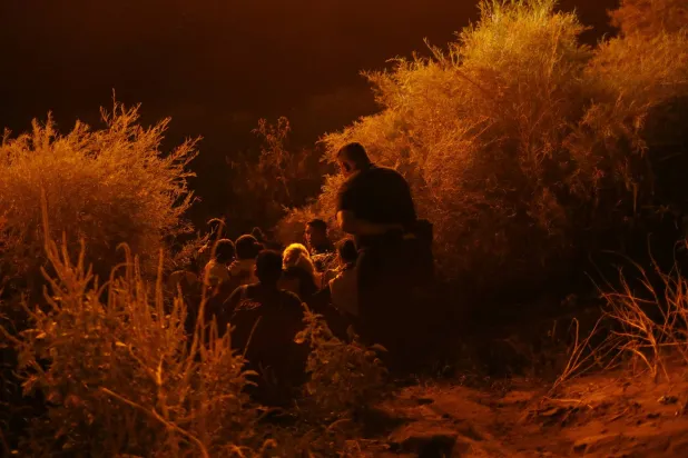 مهاجرون يقفون على ضفة نهر ريو برافو حيث يمنعهم الحرس الوطني في تكساس من العبور (رويترز)