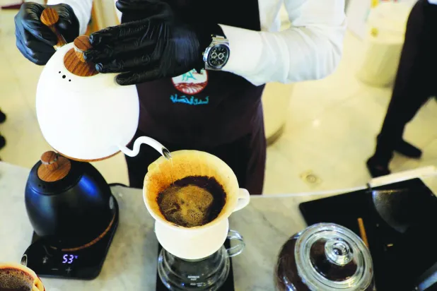 موظف يقوم بإعداد طلب قهوة لأحد العملاء في مقهى (أ.ف.ب)