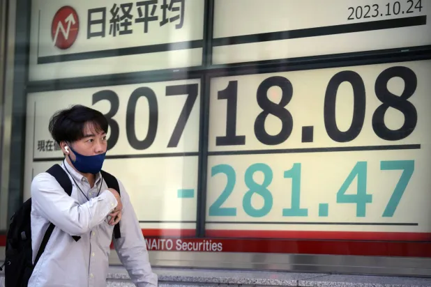 رجل يمر أمام شاشة تعرض تحركات الأسهم على مؤشر «نيكي» الياباني وسط العاصمة طوكيو (أ.ب)