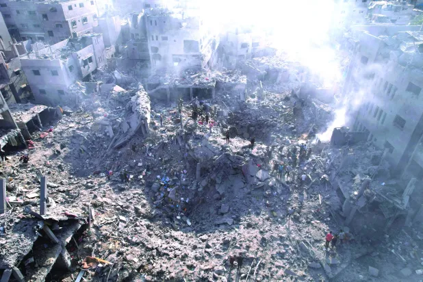 
فلسطينيون يعاينون الدمار الناجم عن غارة إسرائيلية على البريج في قطاع غزة أمس (رويترز)