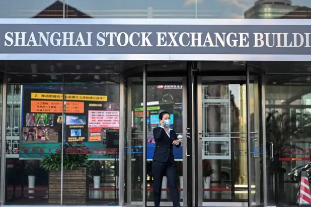 امرأة تغادر مبنى بورصة شنغهاي (غيتي)