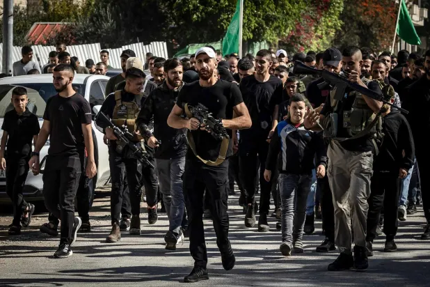 İsrail ordusunun dün Batı Şeria’daki Cenin kampına düzenlediği hava saldırılarında öldürülenlerin cenazesine katılan silahlı kişiler (AFP)