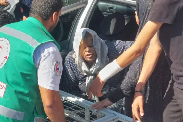 سيدة فلسطينية تصل إلى عربة ويساعدها أحد أفراد الهلال الأحمر في قطاع غزة (وكالة أنباء العالم العربي)