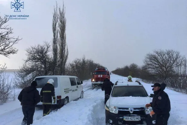 عمال الطوارئ ورجال الشرطة يساعدون أصحاب السيارات العالقة بالثلوج خلال عاصفة في منطقة ميكولايف (رويترز)