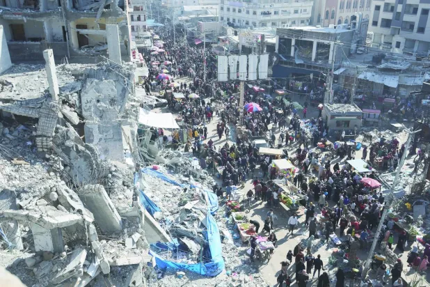 İsrail’in Gazze Şeridi’ndeki Nuseyrat kampını bombalaması sonucu oluşan yıkımın ortasında dün açık pazarda alışveriş yapan Filistinliler (Reuters)