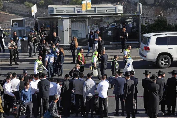 أشخاص ينظرون بينما تقوم قوات الأمن الإسرائيلية وفرق الإنقاذ بفحص مكان إطلاق النار صباح اليوم في القدس، 30 نوفمبر، 2023 (أ.ف.ب)