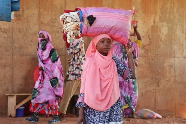 A Sudanese woman fleeing violence in Darfur carries her belongings before crossing into Chad, Nov. 10. (Reuters)